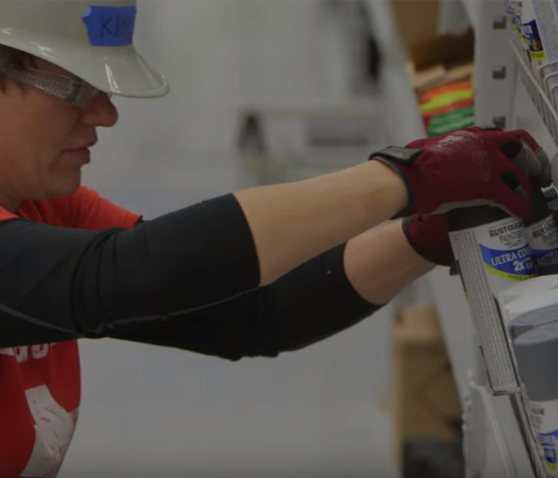 A retail worker places an object on the rack of a retail store